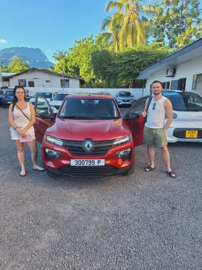 Couple souriant au départ avec une Renault Kwid rouge