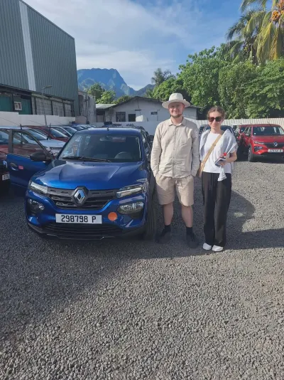Couple devant une Renault Kwid bleue, montagnes de Tahiti en fond