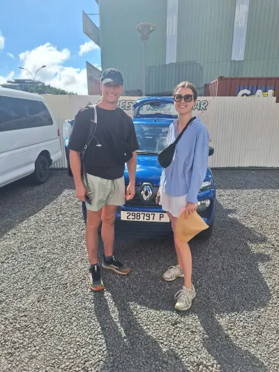 Couple de voyageurs devant leur Renault Kwid bleue