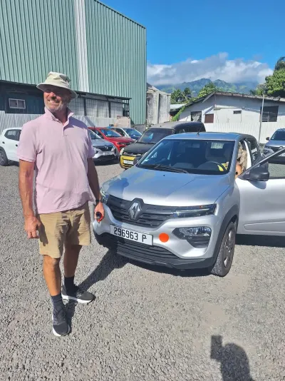 Client au chapeau devant une Renault Kwid grise